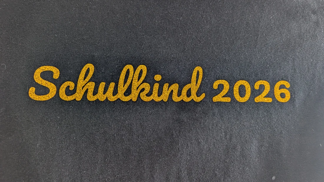 Goldglitzernder Schriftzug Schulkind 2026 auf dunklem Shirt