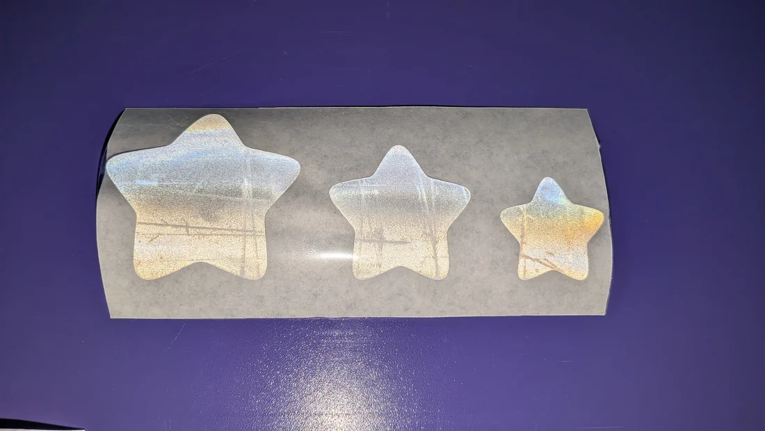 Drei reflektierende Sterne in drei Größen auf der Trägerfolie